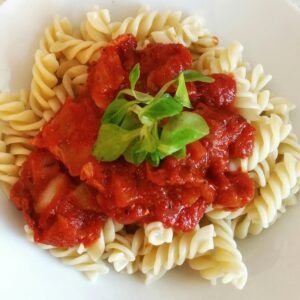 Spirelli pasta topped with rich tomato sauce and fresh greens for a perfect meal.