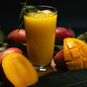 Delicious mango juice with sliced fruit on dark background, highlighting freshness and nutrition.