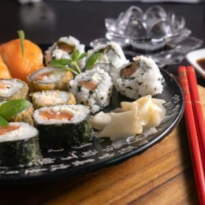 A mouth-watering assortment of sushi served with soy sauce, garnished with fresh herbs, and chopsticks on a wooden board.