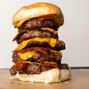 Delicious triple-stacked bacon cheeseburger with melted cheese, perfect for food lovers.