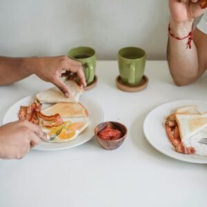 Two people enjoying a casual breakfast of bacon, eggs, and toast.